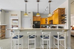 a kitchen with white bar stools and wooden cabinets at Bird's Eye View at Hawk's Eye in Bellaire +23 photos