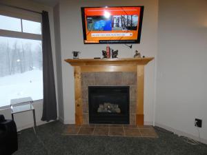 a living room with a fireplace with a television above it at Skier's Slopeside Haven in Bellaire