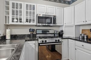a kitchen with white cabinets and a stove and a microwave at Skier's Slopeside Haven in Bellaire