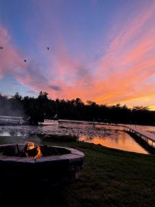 a fire pit next to a body of water at sunset at Driftwood on Torch River in Rapid City