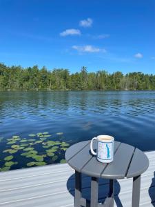 a cup of coffee sitting on a table next to a lake at Driftwood on Torch River in Rapid City