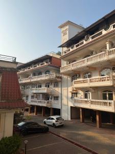 a large building with cars parked in a parking lot at Apartmentbyzaara in Colva