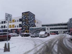 a snowy street with cars parked in a parking lot at River Apartman 2 in Odorheiu Secuiesc
