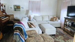 a living room with a white couch and a piano at Sunset View Centennial Farm in Mancelona