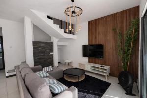 a living room with a couch and a tv at Chalet des Roses in Grand-Baie