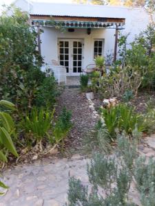 a small white house with a pathway leading to it at Natalie's Garden Cottage, in McGregor
