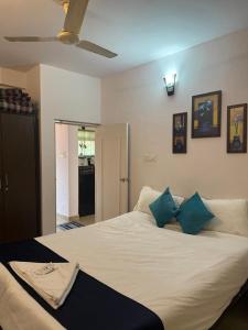a bedroom with a large white bed with blue pillows at Apartmentbyzaara in Colva