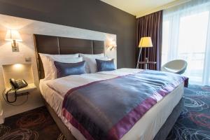 a hotel room with a bed, chair, lamp and window at Aura Hotel Adults Only in Balatonfüred