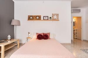 a white bedroom with a large bed with red pillows at CHiC APARTMENT in Tossa de Mar