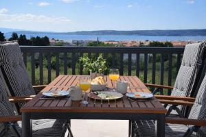 a wooden table with food and drinks on a balcony at GUESTHOUSE Kastel Novi in Kaštela