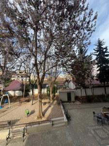 a park with benches and a tree and a playground at Elios Near Centre Apartment in Tirana