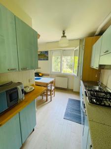 a kitchen with green cabinets and a table with a microwave at Xerxe's House in Varenna