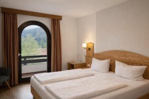 a bedroom with a large bed with a large window at Landhotel Maiergschwendt inkl Chiemgaukarte in Ruhpolding