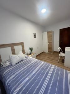 a bedroom with a large bed with a blue striped blanket at O Repouso in Lalín