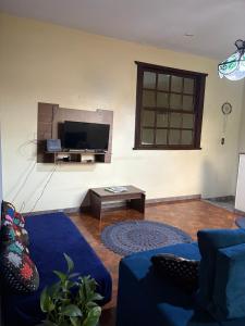 a living room with a blue couch and a tv at NóIS DE CASA HOSTEL & SUÍTES in Belo Horizonte