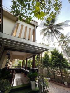 a house with a balcony and a palm tree at Elowen Villa in Mananthavady