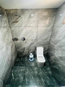 a bathroom with a toilet in a tiled room at Elowen Villa in Mananthavady