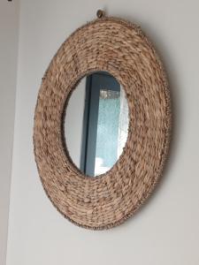 a rattan mirror hanging on a wall with a window at Studio en Luberon in La Bastidonne