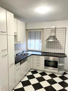 a kitchen with white cabinets and a checkered floor at Ferienwohnung Sophie in Weil am Rhein