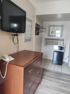 a room with a tv and a dresser with a telephone at Knights Inn London Ontario in London