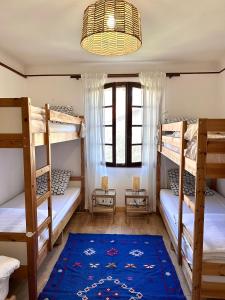 a room with three bunk beds and a blue rug at Yacumama Guesthouse in Soorts-Hossegor