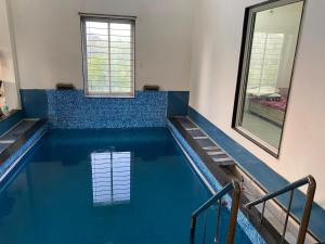 a swimming pool with blue water in a building at Nahta's Farm in Indore