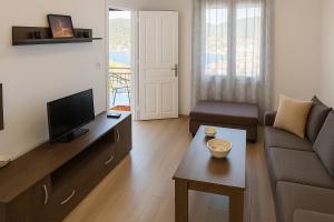 a living room with a couch and a tv at Perioptron Guesthouse Ithaca in Vathi