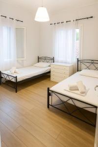 three beds in a room with wooden floors at Perioptron Guesthouse Ithaca in Vathi +11 photos