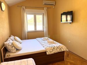 a bedroom with a bed with a window and a television at Central Stay Mostar - Apartments & Rooms in Mostar