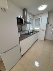 a white kitchen with a sink and a refrigerator at Taína La Encina in Vícar