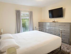 a bedroom with a white bed and a television at London Heathrow Accommodation in Hillingdon