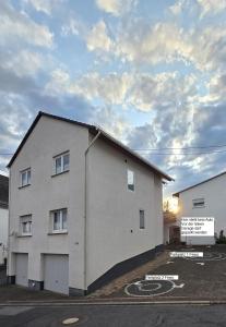 a white building with a sign in a parking lot at Ferienwohnung-Kiefer in Hillscheid