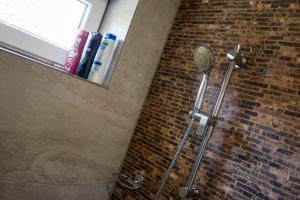 a shower in a bathroom with a brick wall at Villa de Calma Samorin in Šamorín