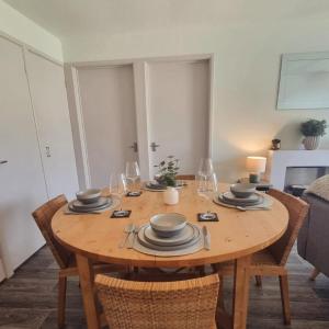 a wooden table with plates and wine glasses on it at 19 the Coombe Charming, 2-Bedroom Family Chalet with Parking, Near Bude Beaches in Bude
