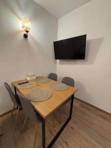 a dining room table with chairs and a flat screen tv at Dimo Cozy Apartments Chisinau Moldova Centre Airport in Chişinău