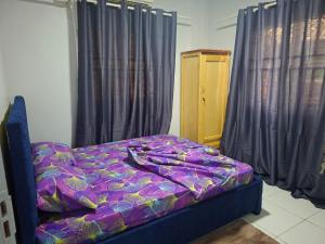a bed with a purple comforter in a room with curtains at Zara Appartement in Paramaribo