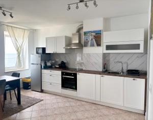 a kitchen with white cabinets and a refrigerator and a table at Blue Coast Ivo in Piran