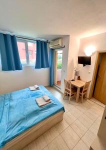 a bedroom with a blue bed and a table at Polo Resort studio in Sunny Beach