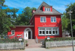 a red house with a white fence in front of it at Seehaus Miersdorf in Zeuthen