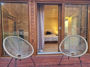 two white chairs sitting on a porch with a bedroom at Szalejówka Domki in Kłodzko +75 photos