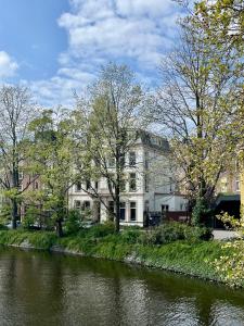a building on the side of a river with trees at Spinoza Suites in Amsterdam