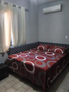 a bedroom with a bed with a red and white blanket at Hostel caminho da Serra in São Pedro