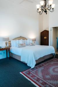 a bedroom with a large bed and a chandelier at Le Petit Paris in Franschhoek