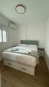 a white bedroom with a bed with a mirror above it at Azahar Home Sevilla in Seville