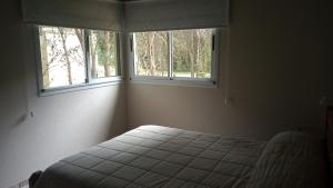 a bedroom with a bed and two windows at Bosque y Mar in Mar Azul
