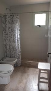 a bathroom with a toilet and a shower curtain at Bosque y Mar in Mar Azul +18 photos