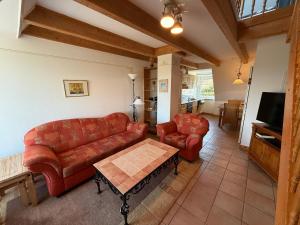 a living room with red couches and a table at Sütjers Hüs in Norddorf