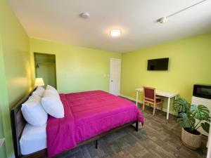 a bedroom with a large bed with a pink blanket at Persepolis Inn in Niagara Falls