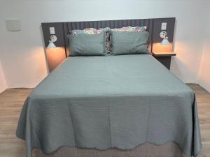 a bedroom with a bed with a green comforter and two lamps at Estúdio com suíte super confortável no centro in Ijuí
