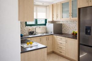 a kitchen with wooden cabinets and a stainless steel refrigerator at Elysian Seaside Villa in Almyrida